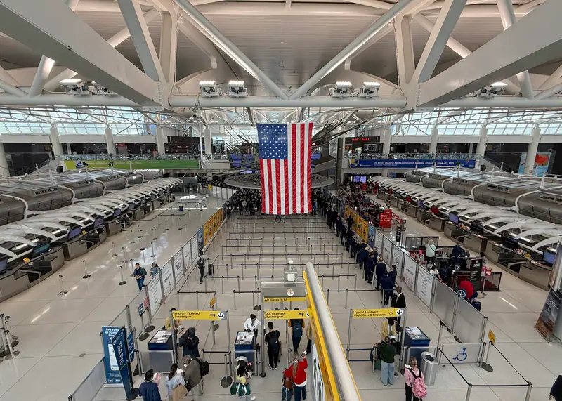 The check-in hall of JFK Terminal 1 with an American flag hanging from the roof