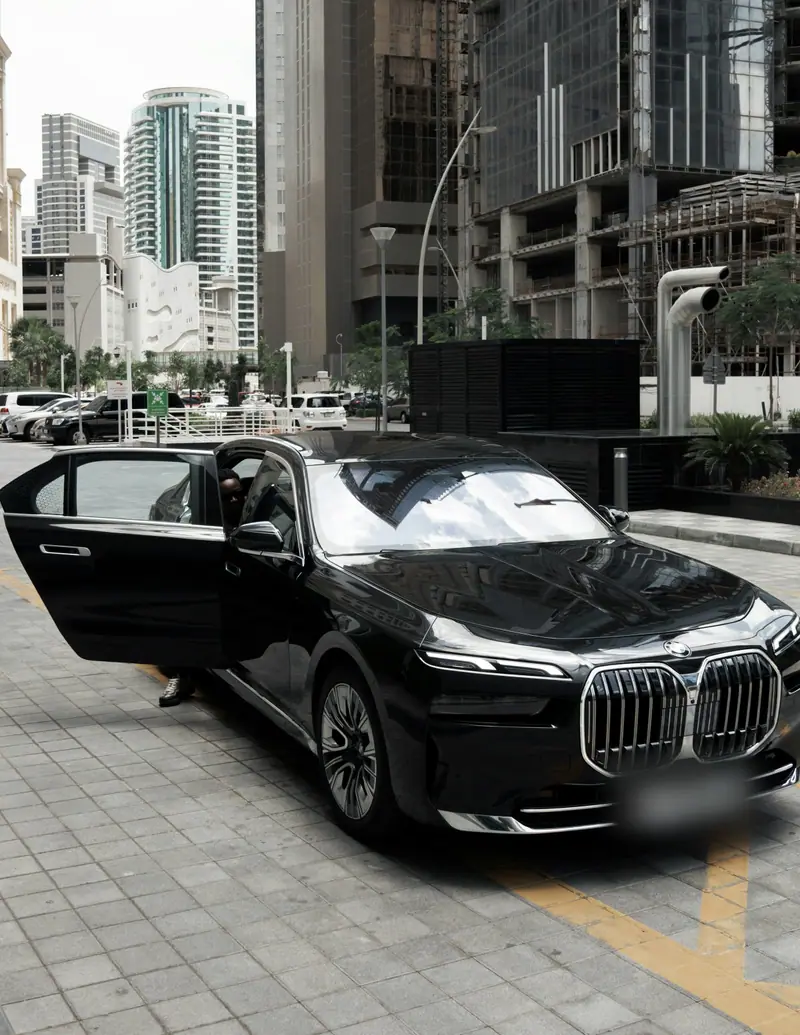 A black BMW 7 Series waits on a city street with its rear door open