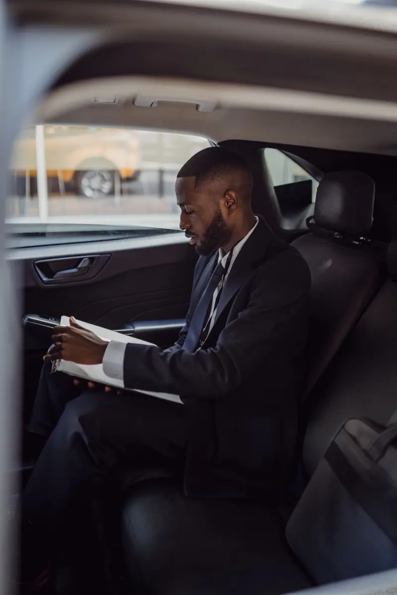 An executive reads documents in the back seat of a car